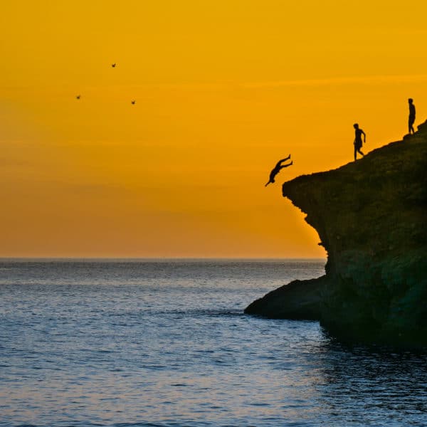Photo au soleil couchant de jeunes sautant d'une falaise